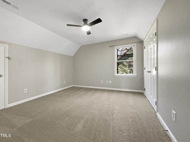 additional living space with baseboards, visible vents, a ceiling fan, vaulted ceiling, and carpet flooring