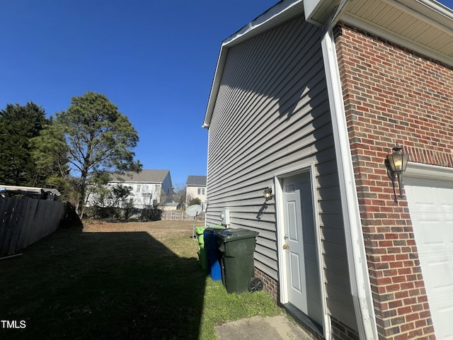 view of side of property featuring a garage, brick siding, and fence