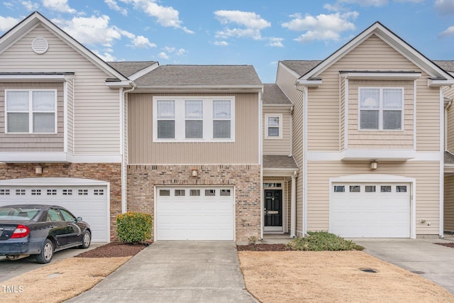 townhome / multi-family property with a garage, brick siding, driveway, and a shingled roof