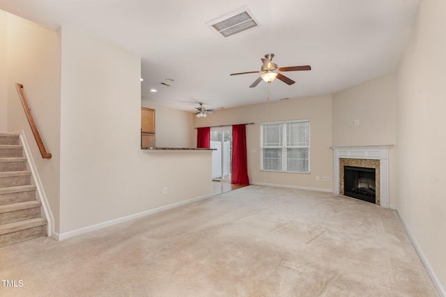 unfurnished living room featuring light carpet, baseboards, visible vents, a ceiling fan, and stairs