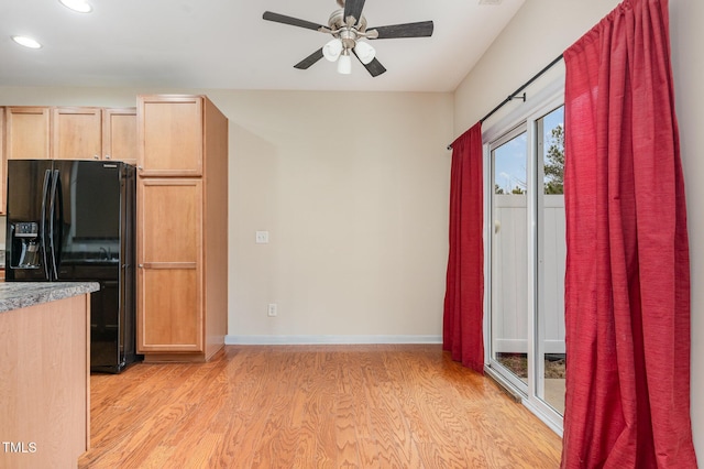 kitchen featuring black fridge with ice dispenser, a ceiling fan, light brown cabinets, light wood-type flooring, and baseboards