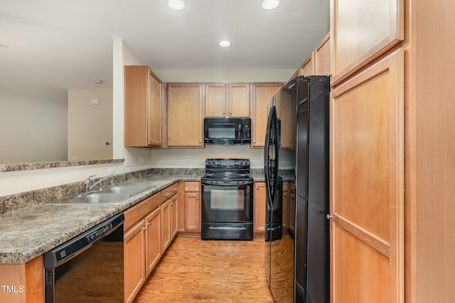 kitchen featuring a peninsula, light wood-type flooring, black appliances, a sink, and recessed lighting