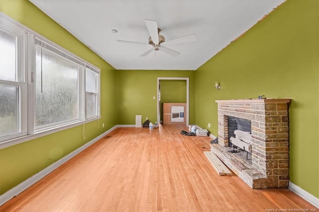 unfurnished living room featuring baseboards, ceiling fan, a brick fireplace, and wood finished floors