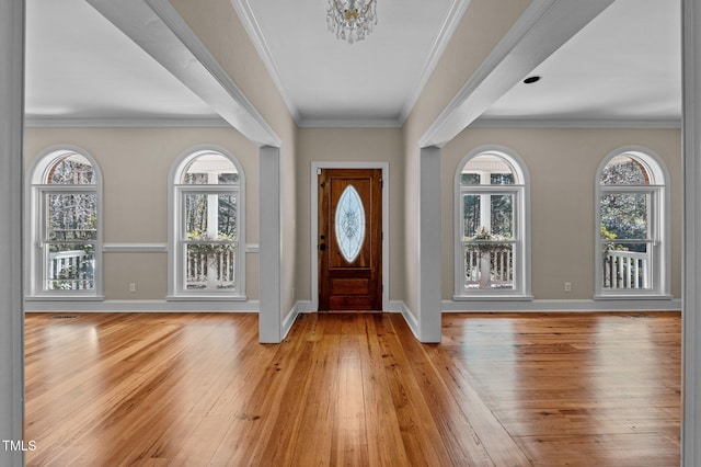 entryway with light wood-style floors, a wealth of natural light, crown molding, and baseboards