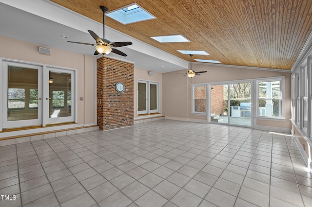 unfurnished living room featuring ceiling fan, vaulted ceiling with skylight, light tile patterned flooring, wooden ceiling, and baseboards