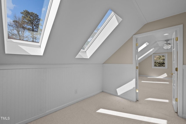 bonus room with vaulted ceiling with skylight, a ceiling fan, and carpet flooring