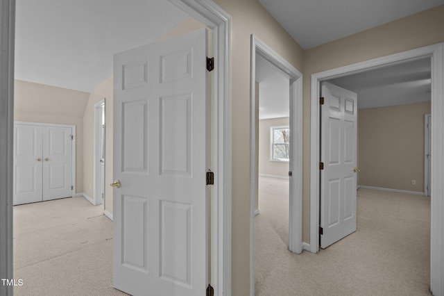 hallway featuring light carpet and baseboards