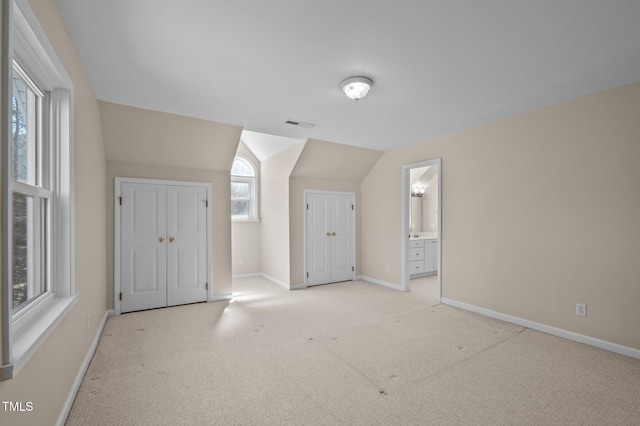 additional living space featuring light carpet, vaulted ceiling, visible vents, and baseboards