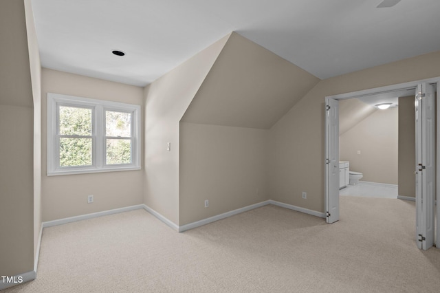 bonus room featuring lofted ceiling, light carpet, and baseboards