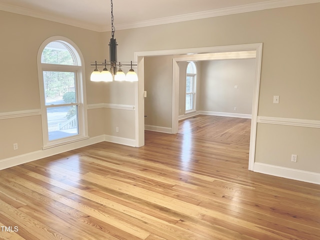 spare room featuring ornamental molding, baseboards, and light wood finished floors