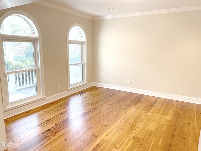 unfurnished room featuring light wood-type flooring, baseboards, visible vents, and ornamental molding