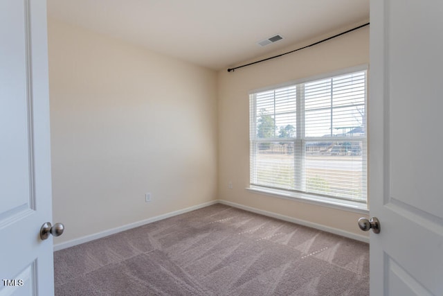 carpeted spare room featuring baseboards and visible vents