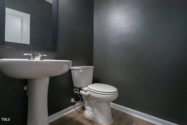 half bathroom featuring toilet, baseboards, and wood finished floors