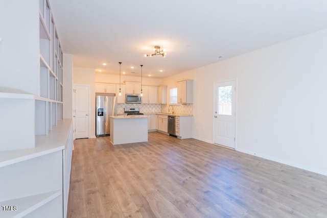 kitchen with tasteful backsplash, open floor plan, a center island, stainless steel appliances, and light wood-style floors