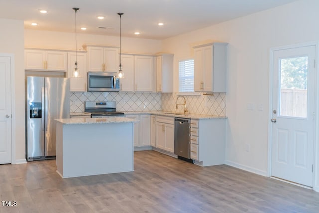 kitchen with tasteful backsplash, a center island, light stone countertops, stainless steel appliances, and a sink