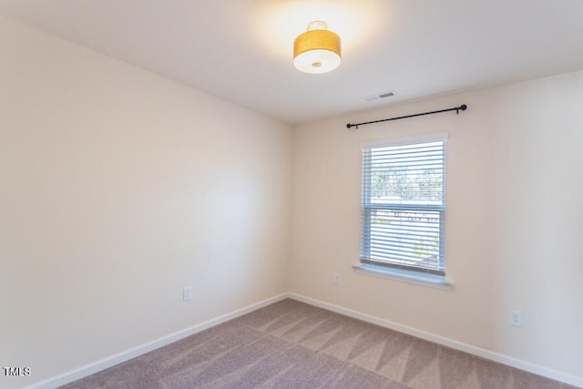 spare room featuring light carpet, visible vents, and baseboards