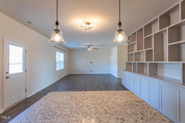 interior space featuring dark wood-type flooring, visible vents, ceiling fan, and baseboards