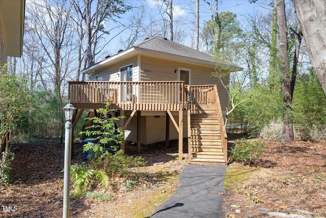 exterior space with roof with shingles, stairs, and a wooden deck