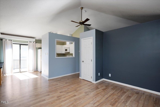 unfurnished room with a ceiling fan, light wood-type flooring, vaulted ceiling, and baseboards