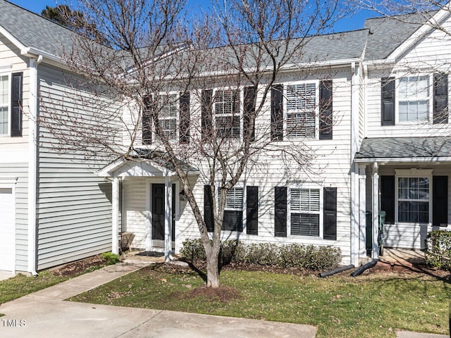 townhome / multi-family property with a shingled roof and a front lawn