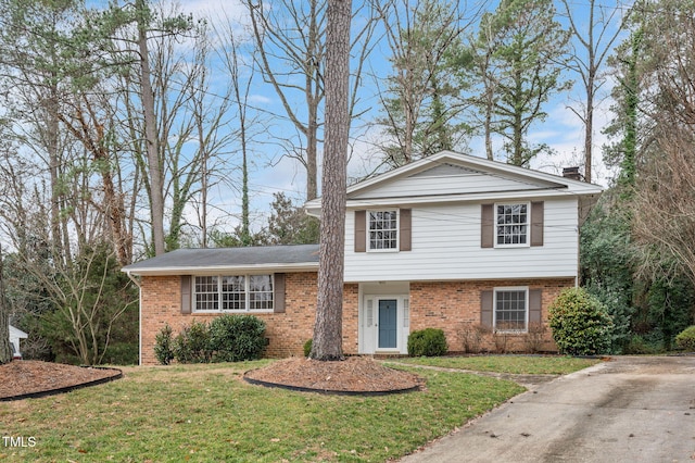 tri-level home with a chimney, a front lawn, and brick siding