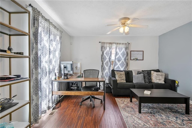 office area with a healthy amount of sunlight, visible vents, ceiling fan, and wood finished floors