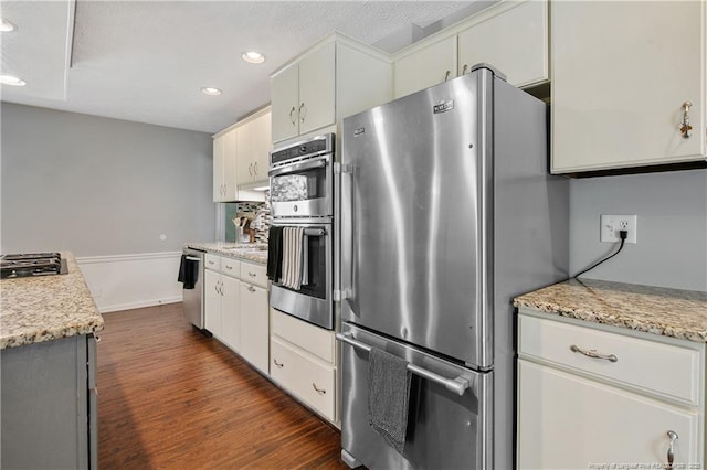 kitchen featuring light stone countertops, appliances with stainless steel finishes, dark wood finished floors, and recessed lighting