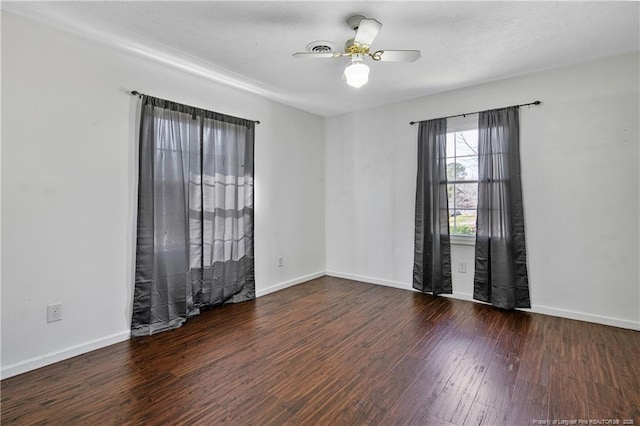 empty room featuring dark wood-style floors, a ceiling fan, and baseboards