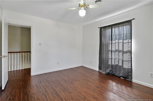 empty room with ceiling fan, visible vents, baseboards, and dark wood-type flooring