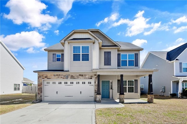 craftsman inspired home with a porch, concrete driveway, a front yard, a garage, and stone siding