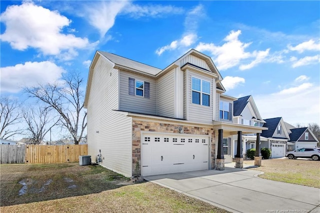 view of front of house featuring central AC unit, a garage, fence, stone siding, and driveway