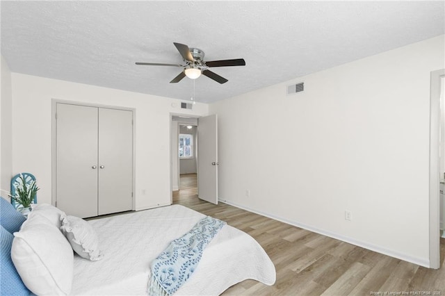 bedroom featuring a closet, visible vents, light wood-style flooring, and a textured ceiling