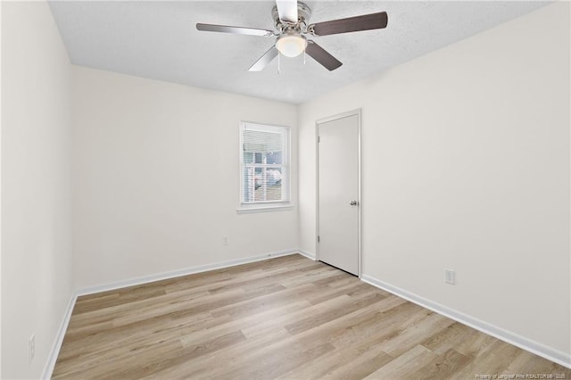 spare room featuring a ceiling fan, light wood-type flooring, a textured ceiling, and baseboards