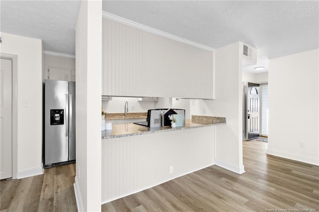 kitchen with stainless steel fridge, visible vents, white cabinets, and light wood-style flooring