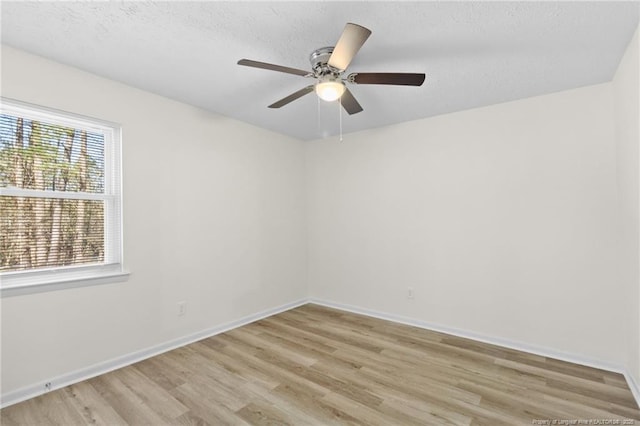 spare room featuring baseboards, ceiling fan, a textured ceiling, and light wood finished floors