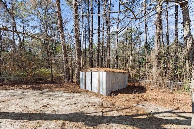 view of yard with an outbuilding, fence, a wooded view, and a storage unit