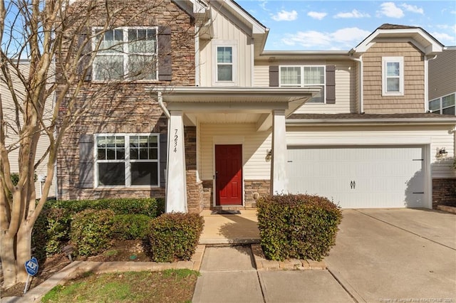 multi unit property featuring stone siding, an attached garage, and concrete driveway