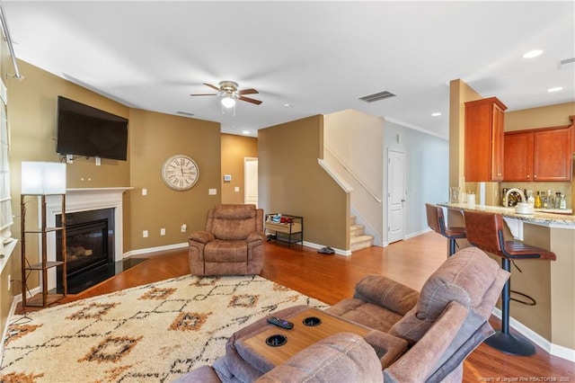 living area featuring a fireplace with flush hearth, stairs, visible vents, and baseboards