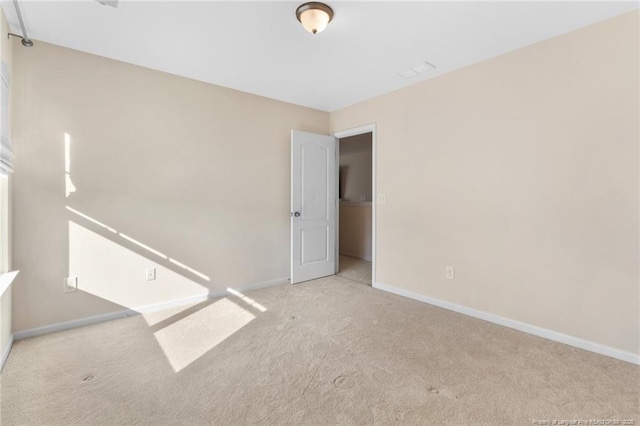 empty room featuring light carpet and baseboards