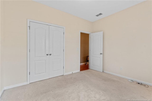 unfurnished bedroom with light carpet, a closet, visible vents, and baseboards