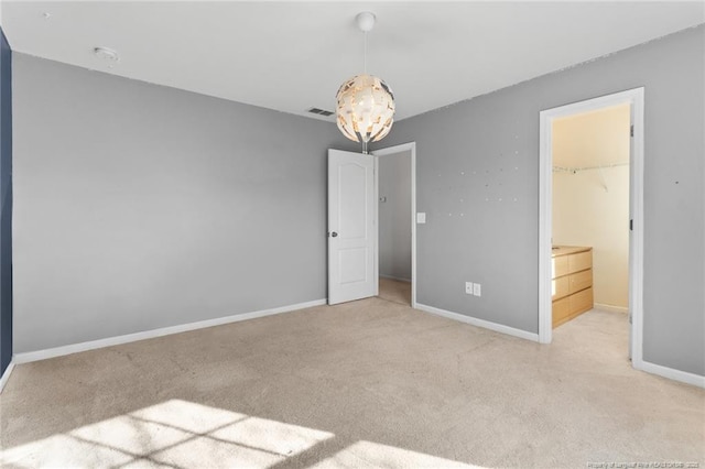 unfurnished bedroom featuring light colored carpet, a notable chandelier, visible vents, and baseboards