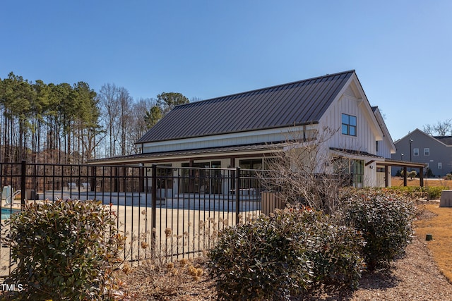 back of house with a patio area, a community pool, fence, and metal roof