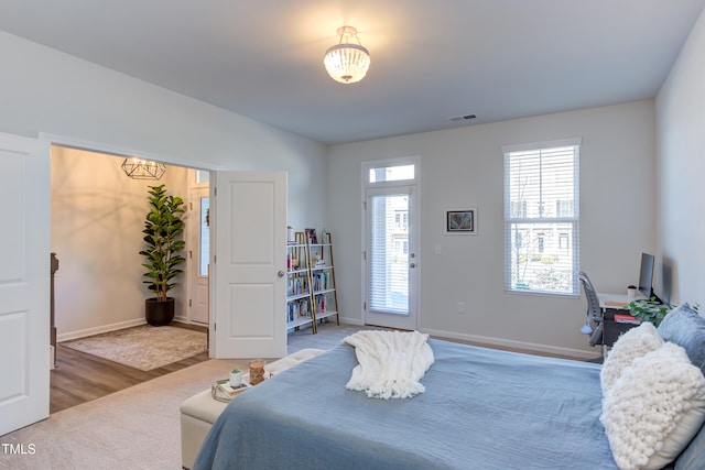 bedroom with wood finished floors, visible vents, and baseboards