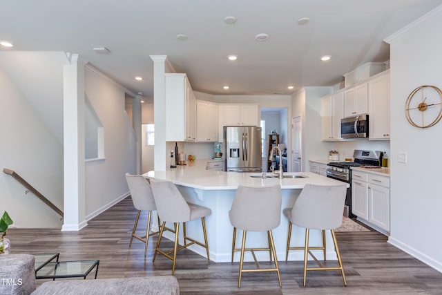 kitchen featuring light countertops, appliances with stainless steel finishes, white cabinets, a peninsula, and a kitchen breakfast bar