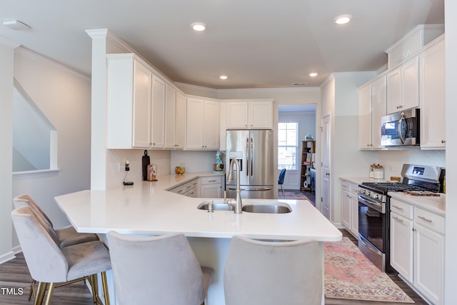 kitchen featuring stainless steel appliances, light countertops, a kitchen bar, and white cabinetry