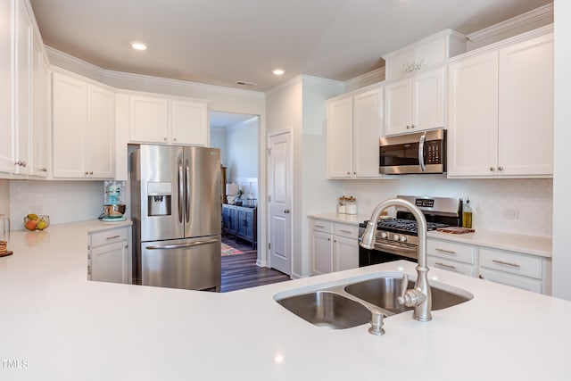 kitchen with appliances with stainless steel finishes, white cabinets, light countertops, and a sink