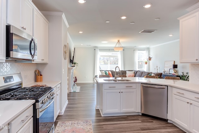 kitchen with a sink, stainless steel appliances, open floor plan, and light countertops