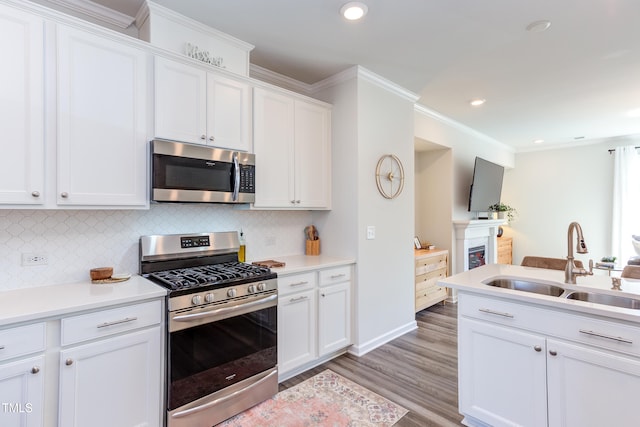 kitchen featuring a sink, white cabinetry, light countertops, ornamental molding, and appliances with stainless steel finishes