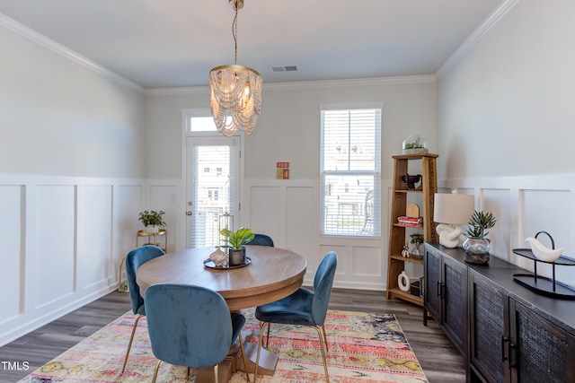 dining room with crown molding, visible vents, a decorative wall, and dark wood-type flooring