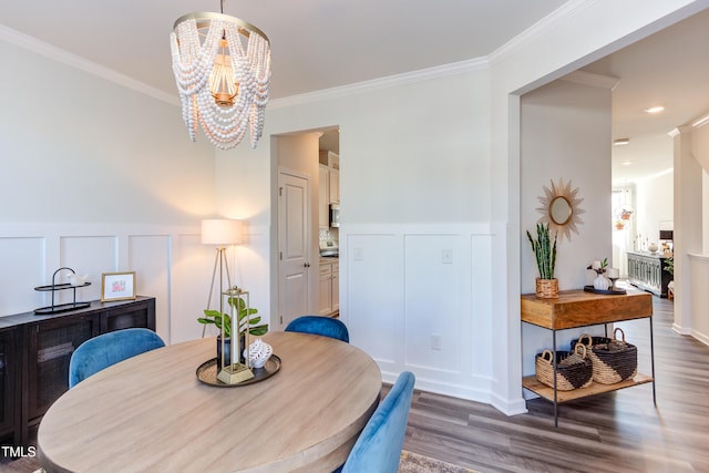 dining space with an inviting chandelier, crown molding, a decorative wall, and dark wood-type flooring